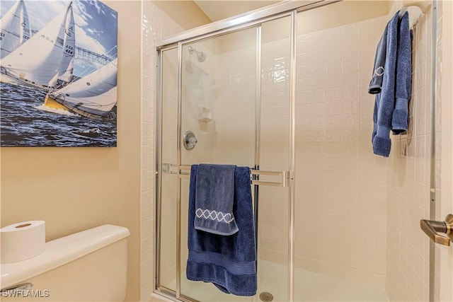 bathroom featuring toilet and a shower with shower door