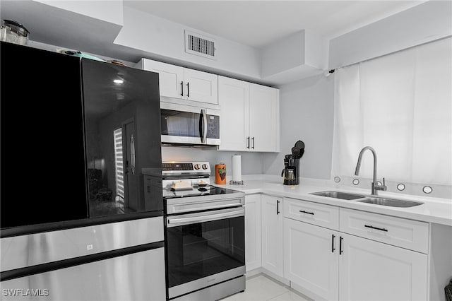 kitchen featuring sink, white cabinetry, stainless steel appliances, and light tile patterned floors