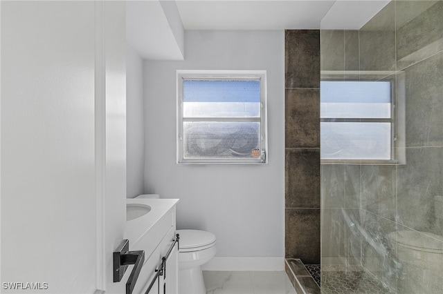 bathroom featuring toilet, a tile shower, and vanity