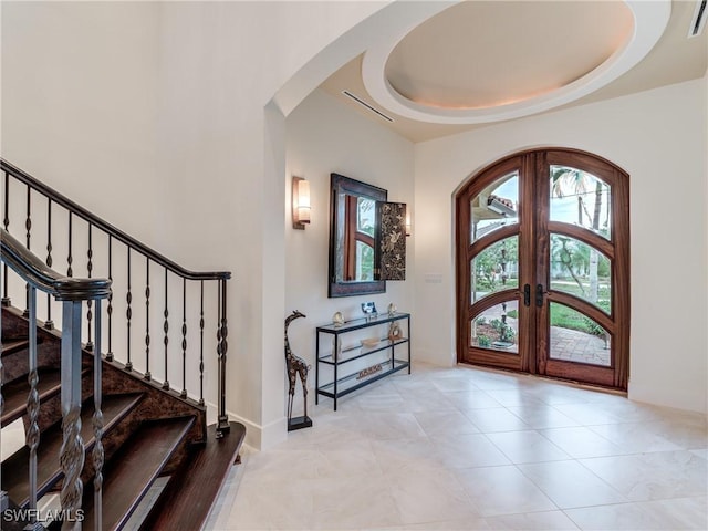 entrance foyer with arched walkways, visible vents, french doors, stairway, and a tray ceiling