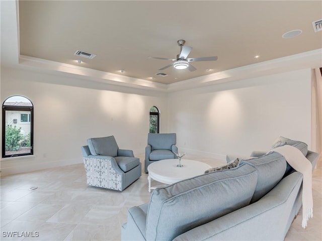 living area with a raised ceiling, visible vents, and baseboards