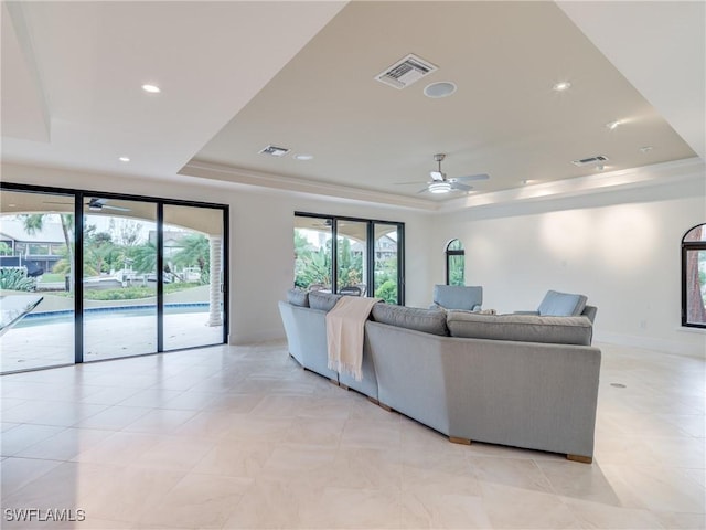 living room featuring a raised ceiling, visible vents, and recessed lighting