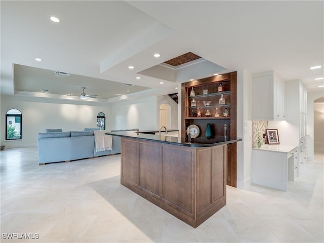 kitchen with arched walkways, visible vents, a tray ceiling, and recessed lighting