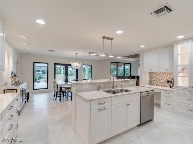 kitchen featuring a center island with sink, tasteful backsplash, visible vents, a sink, and dishwasher