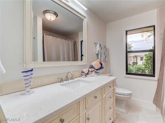 bathroom with toilet, vanity, and baseboards