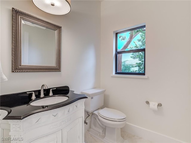 half bath featuring baseboards, vanity, and toilet