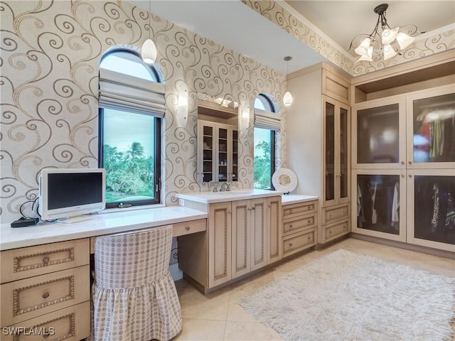 bathroom with tile patterned flooring, a healthy amount of sunlight, a notable chandelier, and vanity