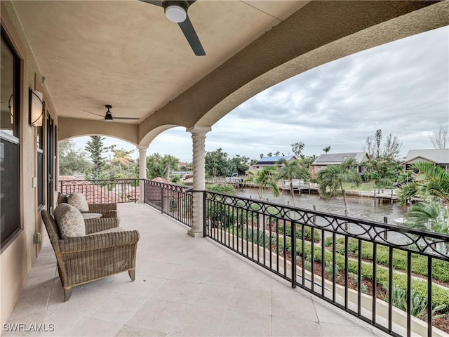 balcony with a water view and a ceiling fan