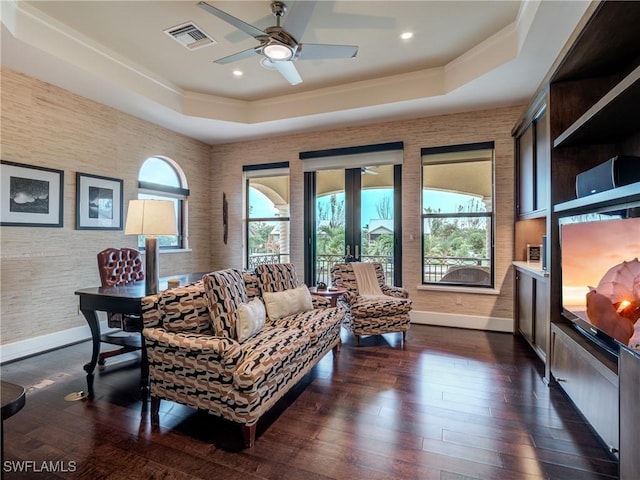 living room featuring visible vents, a tray ceiling, and a wealth of natural light