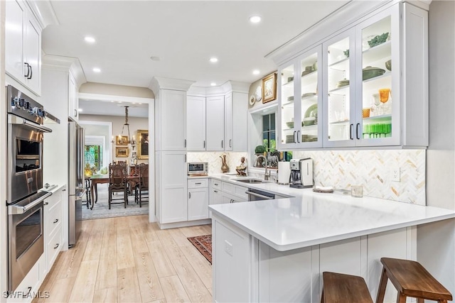 kitchen with tasteful backsplash, a breakfast bar, kitchen peninsula, sink, and white cabinets