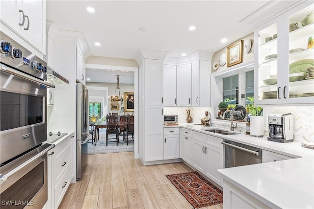 kitchen featuring tasteful backsplash, sink, light hardwood / wood-style flooring, stainless steel appliances, and white cabinets