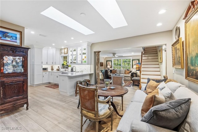 dining room featuring light wood-type flooring, a skylight, and ceiling fan