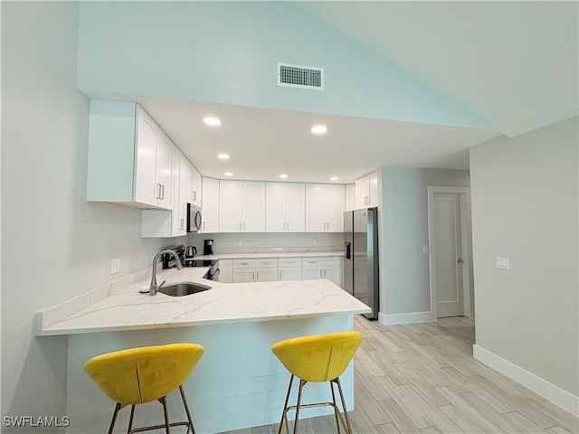 6342 Royal Woods Dr, Fort Myers, FL 33908 - kitchen with visible vents, a peninsula, a kitchen bar, appliances with stainless steel finishes, and a sink