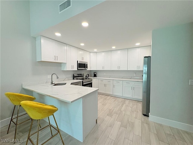 6342 Royal Woods Dr, Fort Myers, FL 33908 - kitchen with light stone counters, a sink, a peninsula, stainless steel appliances, and wood tiled floor