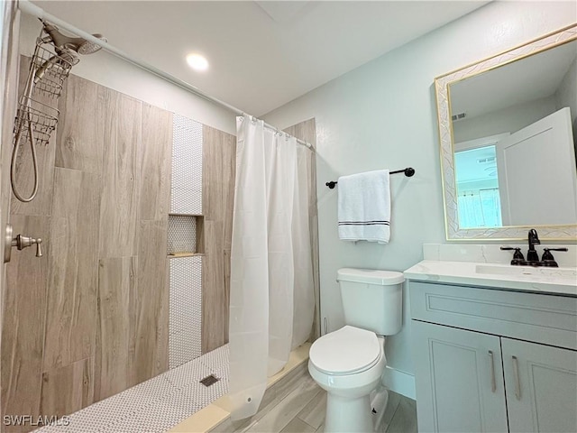 bathroom with wood-type flooring, vanity, toilet, and walk in shower