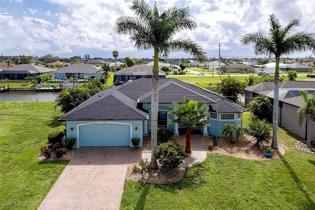 view of front of home with a garage, a water view, and a front lawn