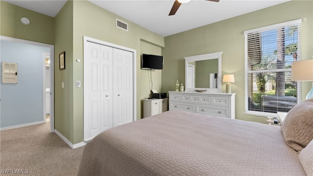 carpeted bedroom with ceiling fan, multiple windows, and a closet