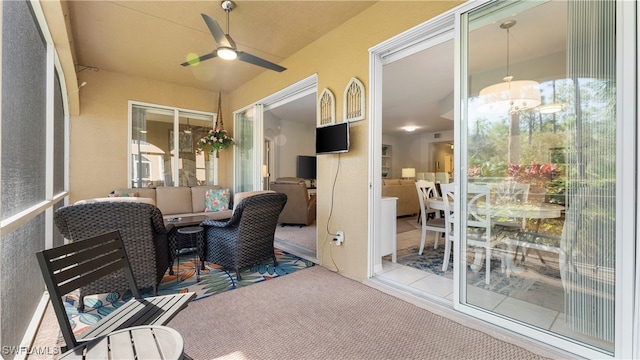 sunroom featuring ceiling fan with notable chandelier