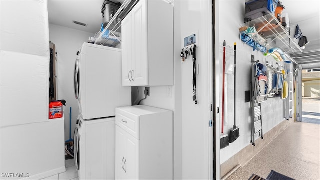 washroom featuring cabinets and stacked washer and clothes dryer