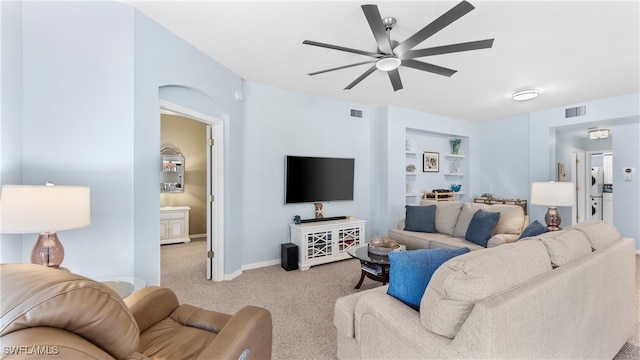 living room featuring light colored carpet, built in features, and ceiling fan