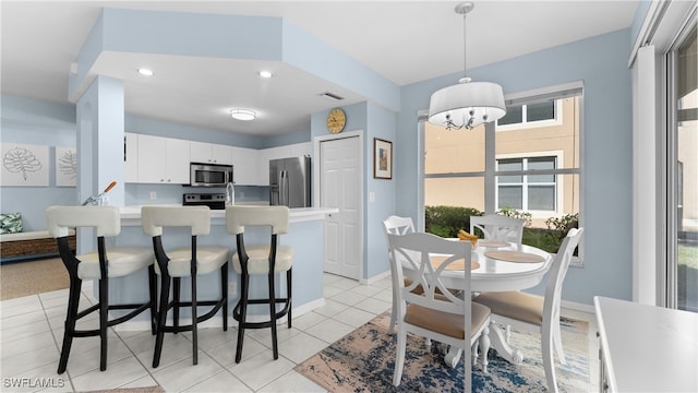 kitchen featuring decorative light fixtures, white cabinetry, stainless steel appliances, a notable chandelier, and light tile patterned floors