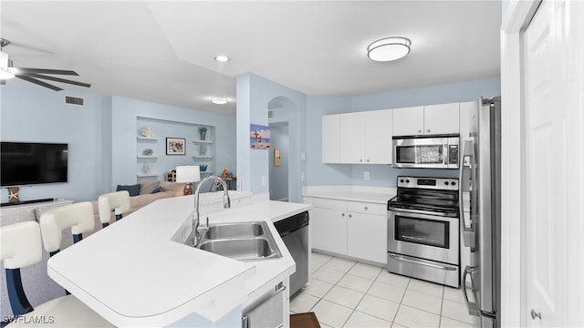 kitchen featuring sink, light tile patterned flooring, white cabinetry, appliances with stainless steel finishes, and an island with sink