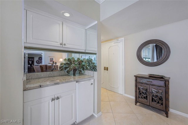 interior space featuring white cabinets, light tile patterned floors, and light stone countertops