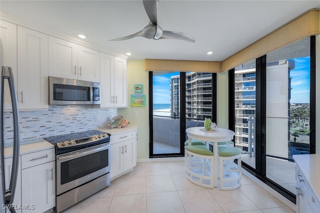 kitchen featuring backsplash, stainless steel appliances, ceiling fan, white cabinets, and light tile patterned flooring