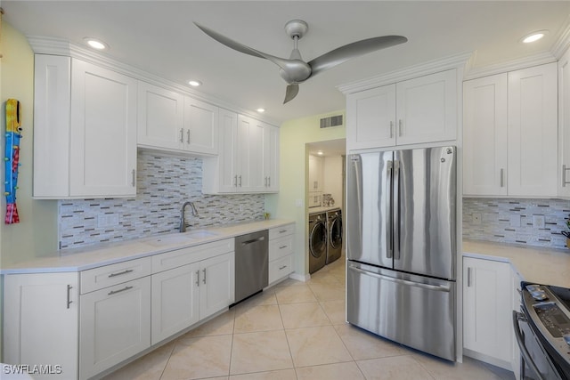 kitchen featuring sink, white cabinets, washer and dryer, and appliances with stainless steel finishes