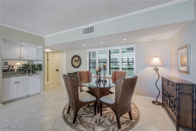 dining room featuring light tile patterned flooring, ornamental molding, and a textured ceiling