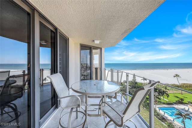 balcony featuring a view of the beach and a water view