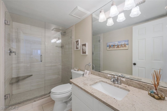 bathroom with vanity, toilet, a shower with door, and an inviting chandelier