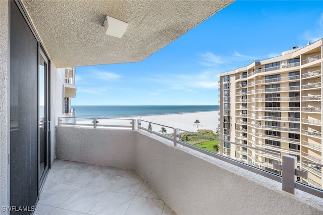 balcony featuring a water view and a beach view