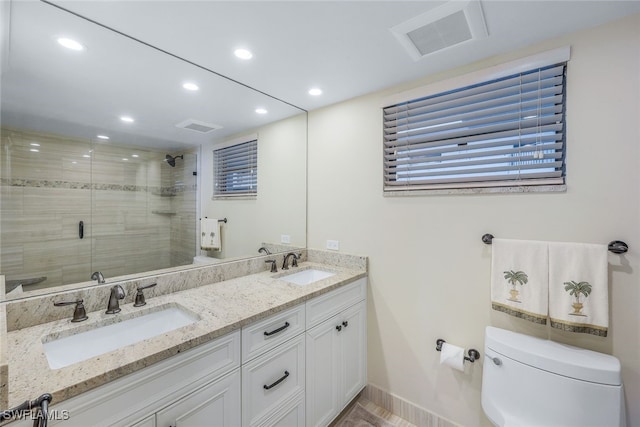 bathroom featuring vanity, toilet, and a shower with door