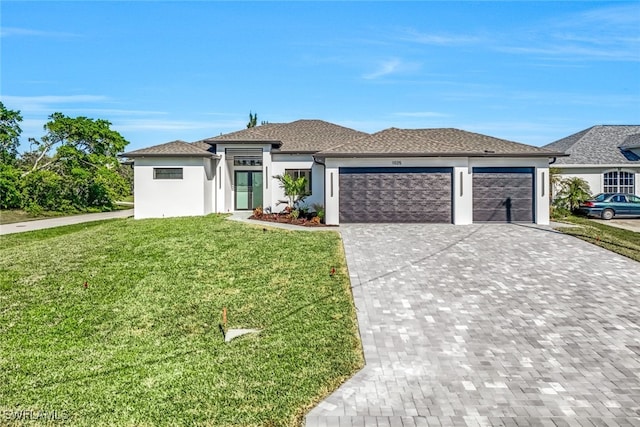 prairie-style house featuring a garage, a front yard, decorative driveway, and stucco siding