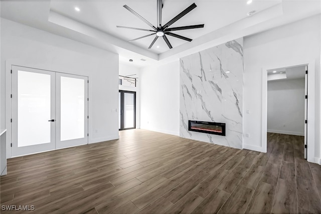 unfurnished living room with a fireplace, dark hardwood / wood-style floors, and a tray ceiling