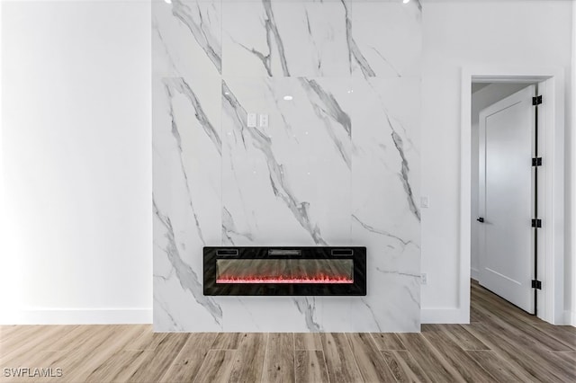 interior details featuring heating unit, a fireplace, wood finished floors, and baseboards