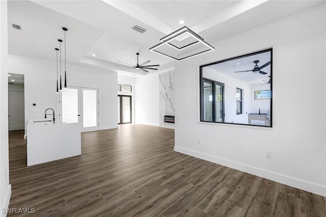 unfurnished living room featuring ceiling fan, plenty of natural light, dark wood-type flooring, and sink