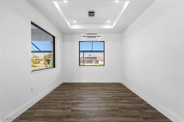 unfurnished room with dark hardwood / wood-style floors and a tray ceiling