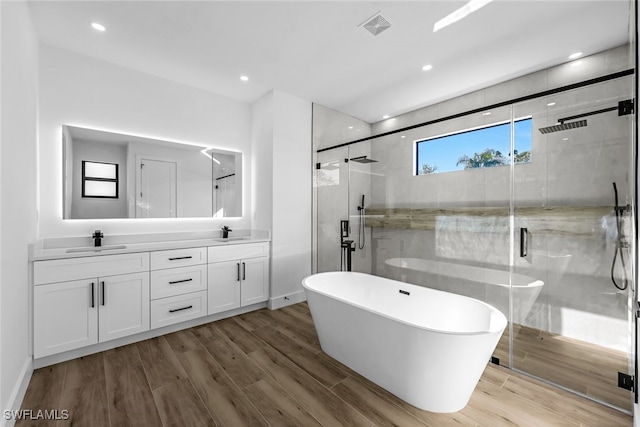 bathroom with a soaking tub, visible vents, a sink, and wood finished floors