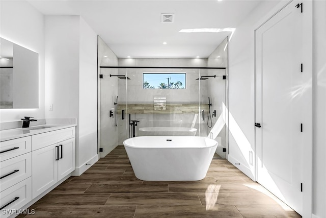 bathroom featuring visible vents, a freestanding bath, vanity, a shower stall, and wood finished floors