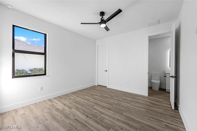 unfurnished bedroom with connected bathroom, light hardwood / wood-style flooring, and ceiling fan