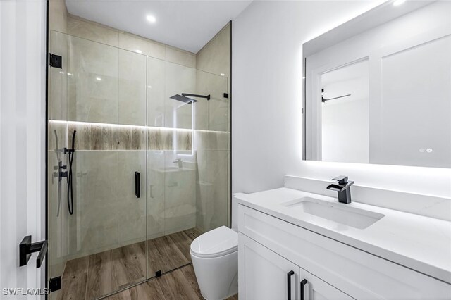 bathroom featuring vanity, hardwood / wood-style flooring, toilet, and an enclosed shower