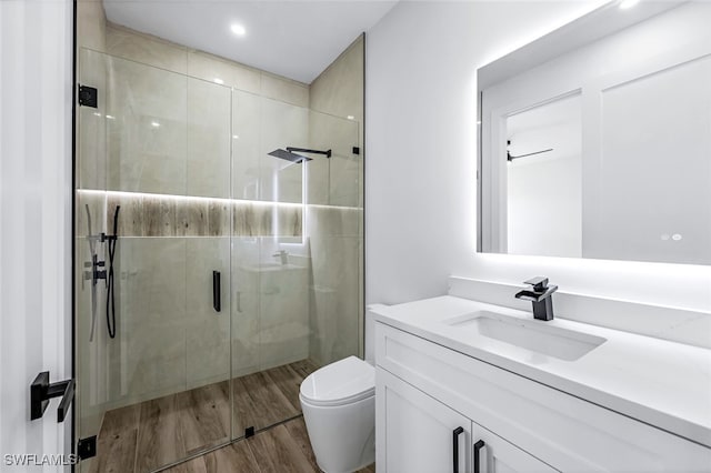 bathroom with toilet, a stall shower, wood finished floors, and vanity