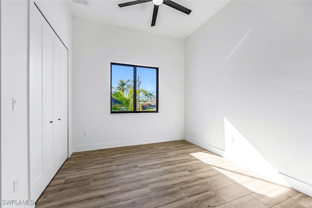 unfurnished bedroom with ceiling fan, light wood-type flooring, and a closet