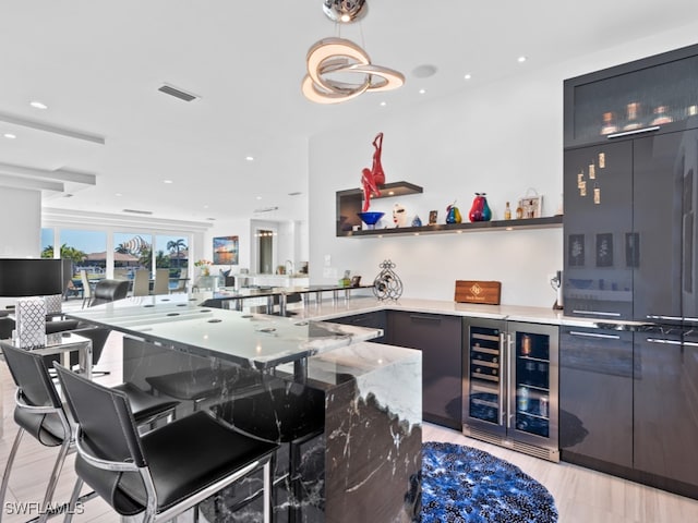 bar with light stone countertops, pendant lighting, beverage cooler, and light hardwood / wood-style floors