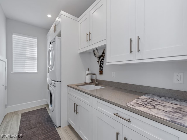 kitchen with white cabinetry, sink, stacked washer / drying machine, and light wood-type flooring