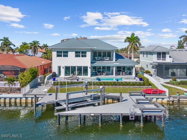 back of property featuring a balcony, a water view, and a pool