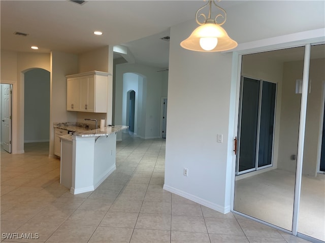 kitchen featuring a breakfast bar, kitchen peninsula, hanging light fixtures, light tile patterned floors, and light stone counters