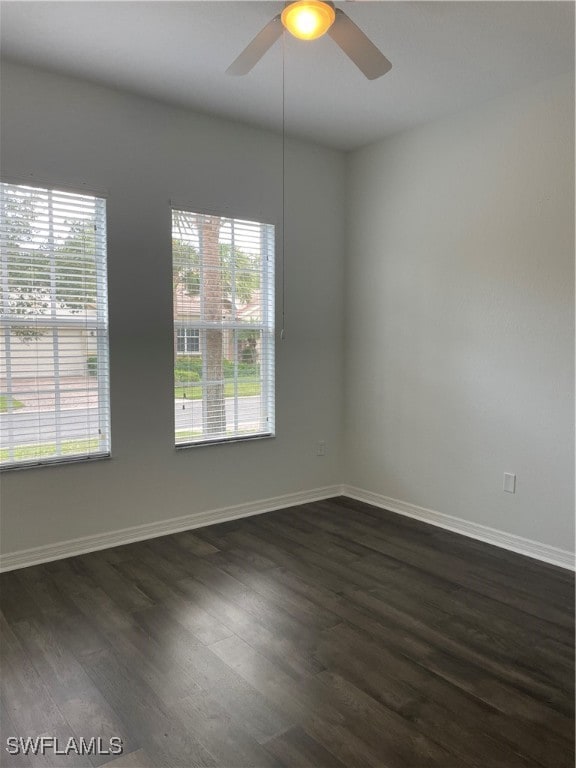 empty room featuring ceiling fan, dark wood-type flooring, and a healthy amount of sunlight